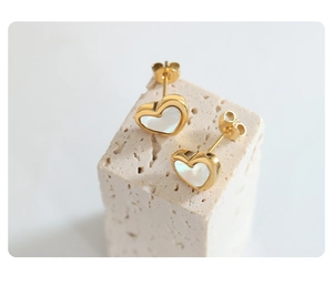Detailed close-up of heart-shaped white seashell earrings with gold metal plating