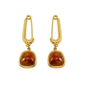 Gold safety pin earrings with amber square stones and twisted rope texture on white background