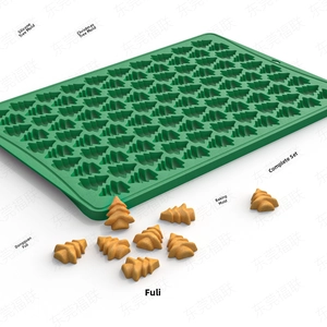 Detailed view of green silicone Christmas tree baking mold with mini cookies