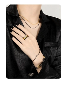 Detailed view of black gold irregular branch texture necklace and rings on a model