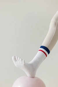 Detailed view of white five-toe yoga socks with red and blue stripes on a pink yoga ball