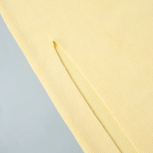 Detailed macro view of high-quality light yellow knit fabric and side slit stitching