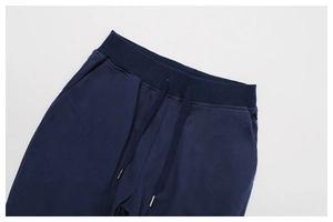 Detail of navy blue knitted sweatpants with elastic ribbed waistband and metal-tip drawstrings