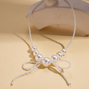Close-up of elegant baroque white faux pearl necklace with a central bow and tassel detail