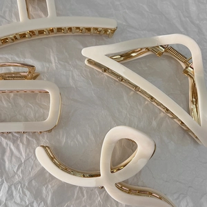 Minimalist cream and gold hair claw clips in various shapes on white paper background