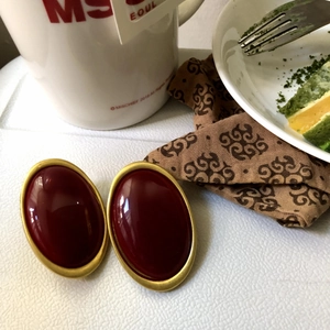 Macro shot of vintage oval earrings featuring deep red resin in a gold metal frame
