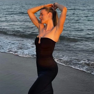 Detail of a black bodycon tube dress on a model at the beach during sunset