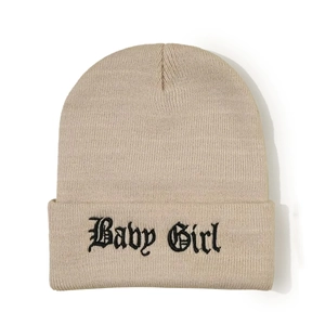 Détail du bonnet en tricot avec broderie gothique 'Baby Girl' sur le revers beige