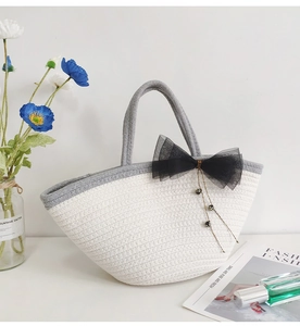 Detail of white cotton woven tote bag with black mesh bow and metal bead decor