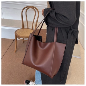 Detail view of a large vintage brown tote bag worn on shoulder in a cozy interior