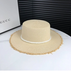 Detail of flat top straw sun hat featuring elegant white pearl band and frayed edges