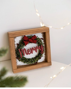 Detail of wooden Christmas sign with Merry text, green wreath and plaid bow accent