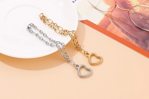 Close-up of gold and silver heart necklaces with rope texture on white ceramic plate