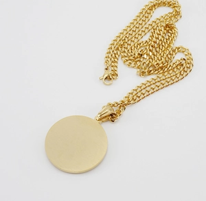 Close-up of 18K gold plated Cuban chain necklace with a brushed matte circular pendant