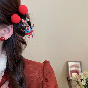 Detail showing a New Chinese style red pompom hair clip with tassels on a braided hairstyle