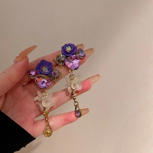 Detail of vintage purple rose earrings with zircon heart and gold droplet fringe