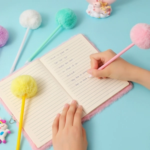 Plush faux fur notebook and pom-pom ball pens set shown in a top-down writing scene