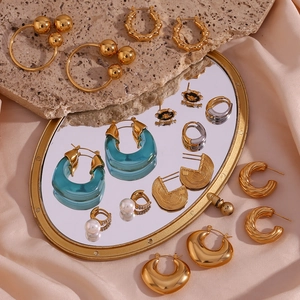 Golden titanium steel earring set with blue resin charms on a silk mirror background