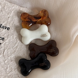 Detailed view of four bone-shaped hair clips in amber, cream, coffee, and black resin