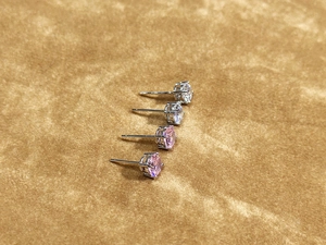Detailed close-up of four-prong round cut studs in clear and pink cubic zirconia