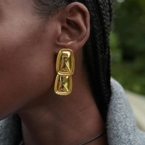 Close-up of gold double-layered geometric rectangle earrings with mirror-polished finish