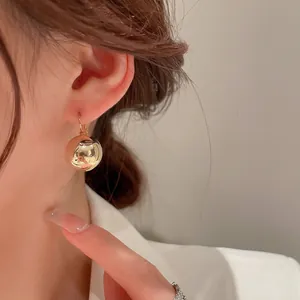 Boucles d'oreilles boules dorées élégantes avec finition métallique polie sur modèle