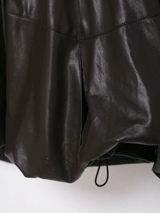 Dettaglio della texture in pelle marrone scuro e cuciture della giacca bomber