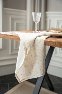 Détail d'une serviette de Noël avec flocons dorés suspendue sur un bord de table en bois