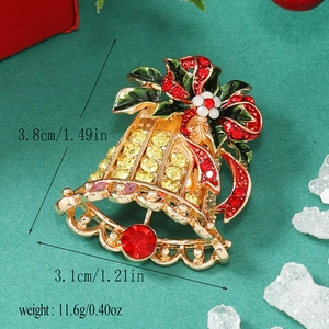 Detailed view of a gold Christmas bell brooch with red and green enamel and rhinestones
