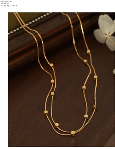 Close-up of golden double-layer chain necklace with geometric square accents
