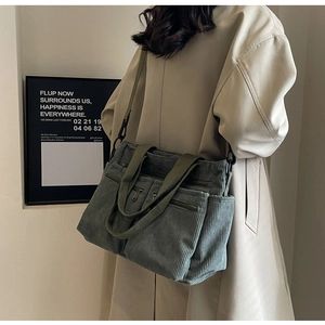 Detail of grey-green corduroy tote bag showing textured pockets and adjustable strap