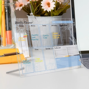 Close-up of a clear acrylic weekly planner on a desk with metal stand and floral design