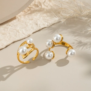 Detail shot of elegant gold geometric rings with white pearls on a minimalist background