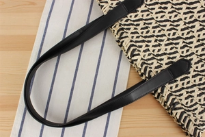 Top view of woven tote bag with geometric beige and black pattern and leather straps