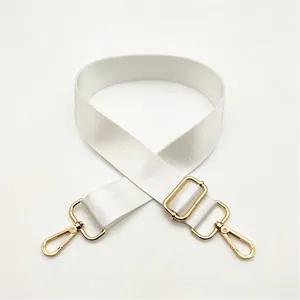 Detail view of adjustable white nylon bag strap with polished gold metal hardware and hooks