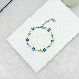 Detail of 18k gold stainless steel bracelet with blue daisies and small stars