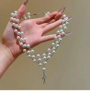 Detail of double-layer pearl necklace featuring a silver cross pendant with zircon inlay