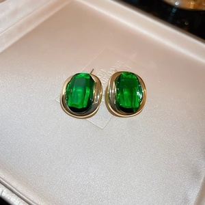 Macro detail of vintage emerald green oval stud earrings with gold plating