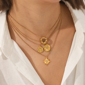 Close-up of layered 18K gold stainless steel necklaces with star and coin pendants