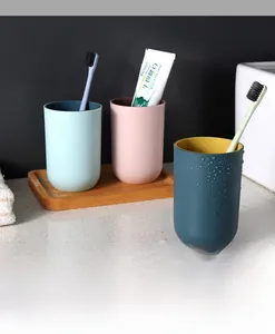 Close-up of minimalist two-tone mouthwash cups in blue, pink and green on a wooden tray