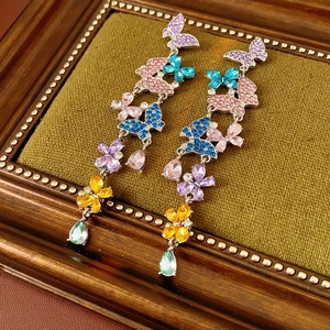 Detail of vintage butterfly earrings with colorful gemstones and a teardrop pendant