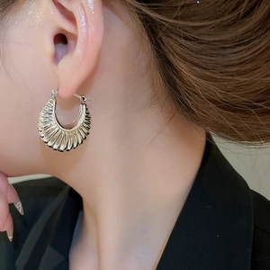 Close-up of chunky silver hoop earrings with textured crinkle finish on female model