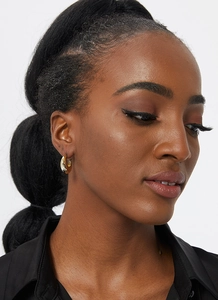 Close-up of chunky gold hoop earrings with polished mirror finish on a female model