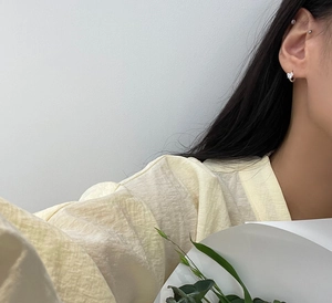 Close-up of minimalist 925 sterling silver hoop earrings with white flower pendant charms