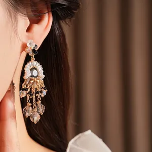Vintage gold tassel earrings with black beads and crystal details worn by a model