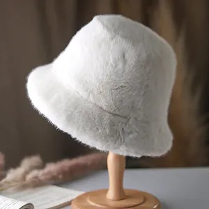 Detailed texture of plush off-white faux fur bucket hat on a wooden stand