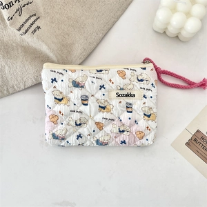 Close-up of quilted cotton cosmetic bag with cute puppy prints and pink braided zipper pull