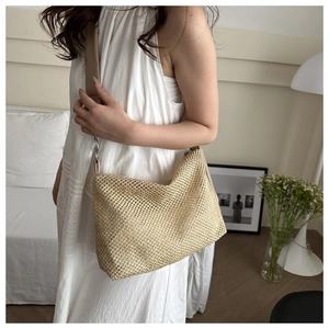 Close-up of beige woven tote bag with mesh texture and leather strap on a shoulder