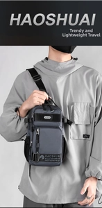 Detail of dark gray nylon sling bag featuring multiple zipper pockets and brand strap