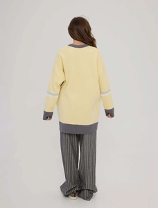 Back view of a yellow oversized knit sweater with grey ribbed trim and striped sleeves